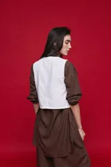 Chaleco blanco de denim con diseño cruzado asimétrico y cierre frontal con tres botones carey.