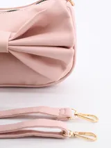 Cartera bandolera negra con moño grande en el frente.