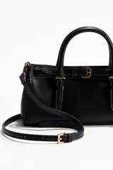 Cartera bandolera rectangular de tejido revestido en color negro, con doble asa superior y trabilla decorativa tipo cinturón con hebilla metálica en el frente. Cuenta con cierre magnético y compartimento interior.