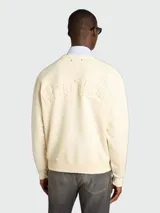 Buzo de algodón de corte holgado, color crema, con cuello redondo y mangas largas. Presenta un diseño minimalista y versátil.