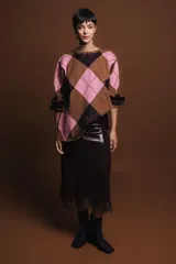Sweater holgado con diseño de rombos en tonos marrón, negro y rosado, con detalles de lurex en las líneas divisorias. Presenta cuello redondo, mangas largas con puños acanalados y un corte relajado.