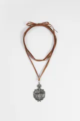 Collar de cordón marrón con dije de escudo plateado con detalles grabados y sol en la parte superior.