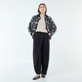 Chaqueta corta con estampado floral en tonos rosa y celeste sobre fondo negro. Tiene cuello mao y cierre frontal con botones a presión.