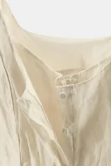 Top de viscosa con diseño efecto arrugado, escote redondo, tirantes finos y cierre frontal con botones ocultos.