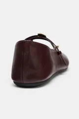 Zapato tipo bailarina de cuero color bordó, con tira ajustable en el empeine, detalle metálico y punta redonda.