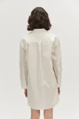 Camisa oversize color blanco, confeccionada en algodón, con cuello clásico, cierre frontal con botones tapados, un bolsillo aplicado en el pecho y mangas largas con puños anchos.