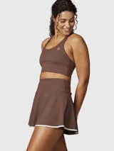 Falda skort deportiva color marrón chocolate, con short integrado y detalle de borde inferior en color blanco. Presenta un diseño de tiro alto y corte acampanado.