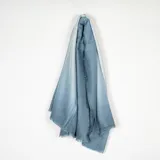Pashmina de textura suave con diseño degradado en tonos azules y bordes desflecados.