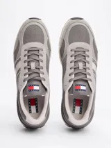 Zapatillas Tommy Jeans grises de corte bajo, con exterior de ante y malla, detalles distintivos de la marca, suela de goma dentada y cierre con cordones.