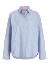 Camisa de manga larga con cuello clásico y cierre frontal de botones. Presenta un diseño a rayas verticales en tonos celestes y blancos, con puños anchos y un corte relajado.