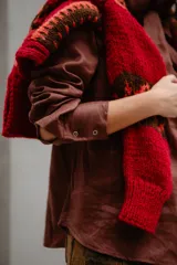 Blusa de lino color marrón con cuello tipo lazo, mangas largas y diseño entallado con pinzas frontales.
