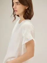 Blusa de lino color rosado, de corte recto y holgado, con cuello redondo y mangas cortas adornadas con volados.
