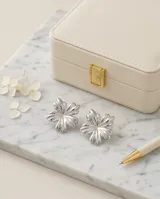 Caravanas de acero con diseño de flor de pétalos redondeados y acabado plateado brillante.