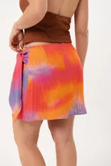 Minifalda multicolor con estampado abstracto en tonos naranja, rosa y violeta. Diseño cruzado con lazo lateral.