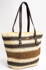 Bolso tipo tote de diseño trenzado con patrón de rayas en tonos marrones y beige, doble asa larga de material sintético oscuro y placa metálica con logo.
