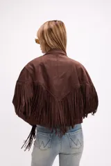 Chaqueta de efecto gamuza en color marrón, con solapas amplias, cierre frontal con botón y flecos largos decorativos en la parte frontal y trasera. Presenta un diseño estructurado de estilo western.