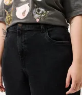 Pantalón de jean estilo mom, color negro, tiro alto, corte holgado en caderas y piernas, con bolsillos funcionales y cierre frontal.