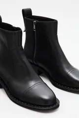Botas de cuero negras con punta redonda, detalle de tachas en la suela y cierre lateral.