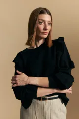 Sweater negro de manga larga, tejido suave y caída liviana, con volados en el delantero y mangas. Silueta recta.