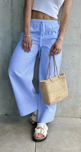 Pantalón pijamero celeste a rayas verticales blancas, de corte ancho y cintura con cordón ajustable.