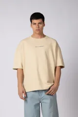 Remerón de corte oversized confeccionado en tejido rústico, con cuello redondo y mangas cortas. Presenta un diseño minimalista con una pequeña estampa frontal centrada en el pecho.