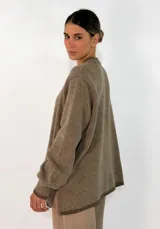 Sweater de tejido de punto en color azul marino, con cuello redondo, mangas largas con puños acanalados y ajuste holgado. Presenta un pequeño aplique decorativo en el ruedo.