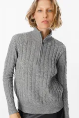 Sweater de punto gris con textura de ochos, cuello alto con cierre frontal parcial, manga larga y puños y ruedo acanalados.