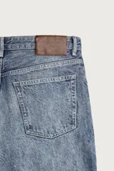 Pantalón jeans de corte relaxed fit, color azul con efecto ligeramente lavado, perneras rectas con raya de planchado frontal y diseño de cinco bolsillos.