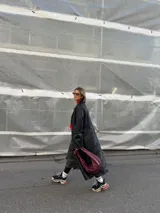 Cartera tipo hobo de cuero color borgoña con asa superior anudada.