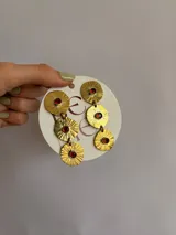 Caravanas colgantes de bronce con diseño de tres discos texturizados en degradé, cada uno con una circonia roja engarzada en el centro. Cuentan con perno de plata 925.