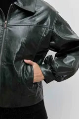 Cazadora de estilo bomber confeccionada en material efecto piel color verde oscuro. Presenta cuello camisero, cierre frontal con cremallera, mangas largas abullonadas con puños elásticos y un corte ligeramente cropped.