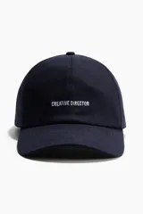 Gorra de sarga de algodón color azul marino, con diseño bordado frontal con la frase "Creative Director" en color blanco y visera curva.