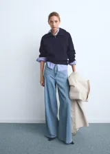 Pantalón de jean estilo denim con corte de pierna ancha y cintura alta. Presenta dos bolsillos de parche en la parte delantera, dos bolsillos traseros, trabillas para cinturón y cierre frontal con botón y cremallera.