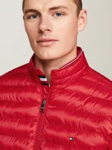 Campera acolchada roja de poliéster reciclado, con cuello alto, cierre de cremallera, bolsillos laterales y logo de Tommy Hilfiger bordado en el pecho.