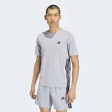 Remera deportiva Adidas de manga corta, color gris claro, con cuello redondo y diseño de las tres rayas características de la marca en color negro sobre los laterales. Presenta el logo de la marca en el pecho.