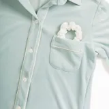 Pijama de dos piezas color rosa pálido, confeccionado en terciopelo. La camisa es de manga larga con botones frontales y bolsillo en el pecho. El pantalón es de corte recto con cintura elástica.