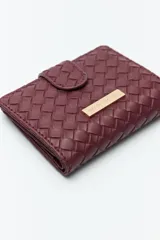 Billetera de mujer Daniel Cassin con diseño trenzado, cierre con broche a presión y placa metálica dorada con el logo de la marca en el frente.