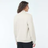 Sweater de punto color beige claro, con cuello alto y cierre frontal parcial de cremallera. Presenta puños y bajo acanalados.