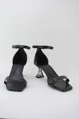 Sandalias negras con punta cuadrada, tira delantera fina y pulsera ajustable al tobillo. Destacan por su taco geométrico transparente de altura media.