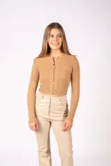 Campera de punto acanalado color fucsia, de corte cropped y manga larga. Presenta cierre frontal con tirador decorativo y detalle de tachas metálicas circulares en la parte inferior.
