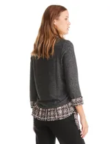 Buzo de tejido fino color beige con diseño de doble capa que simula una camisa debajo. Presenta cuello redondo, mangas largas con puños de gasa estampada en animal print, y ruedo con volado de la misma tela. Incluye detalles de frunces en los laterales.