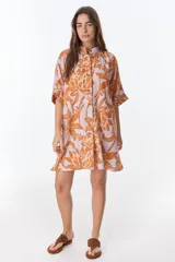 Camisa larga de lino con estampado floral azul sobre fondo beige. Posee cuello mao, mangas cortas con puños, botones metálicos a la vista y tajos laterales en el ruedo.