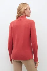 Polera de punto color ladrillo, de cuello alto y mangas largas con cierre en los puños.