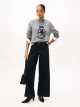 Sweater gris de corte regular y manga raglán, confeccionado en pura lana. Presenta cuello perkins, puños y bajo en punto canalé, y un escudo gráfico distintivo de la marca tejido en el pecho.