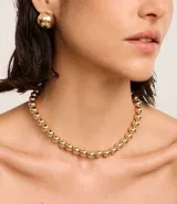 Conjunto de collar corto y caravanas de metal dorado con diseño de esferas lisas.