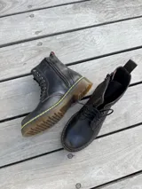 Bota corta de cuero color chocolate, con cordones amarillos y cierre lateral.