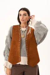 Chaleco oversize confeccionado en cuero descarne, con diseño de terminación en picos, detalle de tachas metálicas en los bordes frontales y flecos en la espalda.