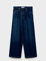 Pantalón de jean estilo wide leg, de tiro medio y color azul oscuro. Cuenta con cierre frontal de cremallera y botón, cinco bolsillos y trabillas para cinturón.