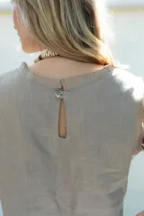 Top de lino sin mangas color salmón, con escote redondo y terminaciones desflecadas en cuello y hombros. Cuenta con cierre trasero de botón de coco.