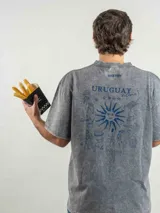 Remera de corte oversize color marrón con efecto lavado, cuello redondo y estampa frontal con la frase 'URUGUAY noma!'.